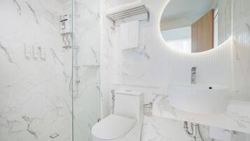 Un baño moderno con ducha de vidrio, inodoro y lavabo con espejo.