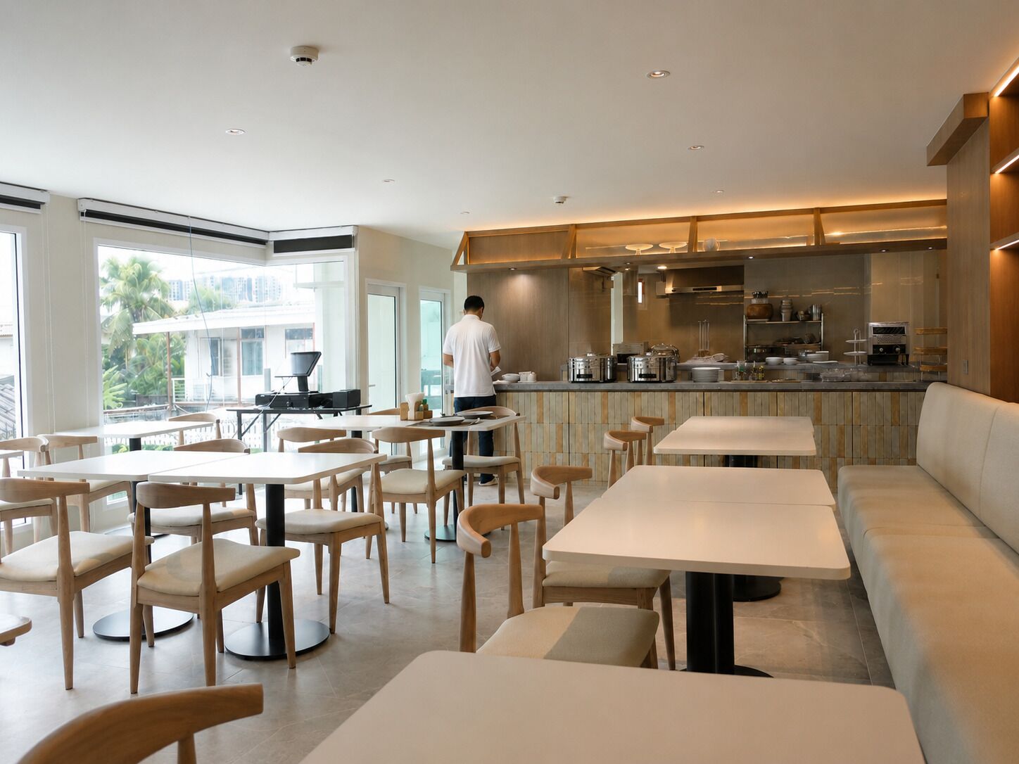 Un comedor moderno con mesas y sillas, una zona de bar y vistas al exterior.