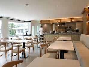 A modern dining area with tables and chairs, a bar area, and a view of the outside. - Surestay By Best Western Siriraj Bangkok (Bangkok)