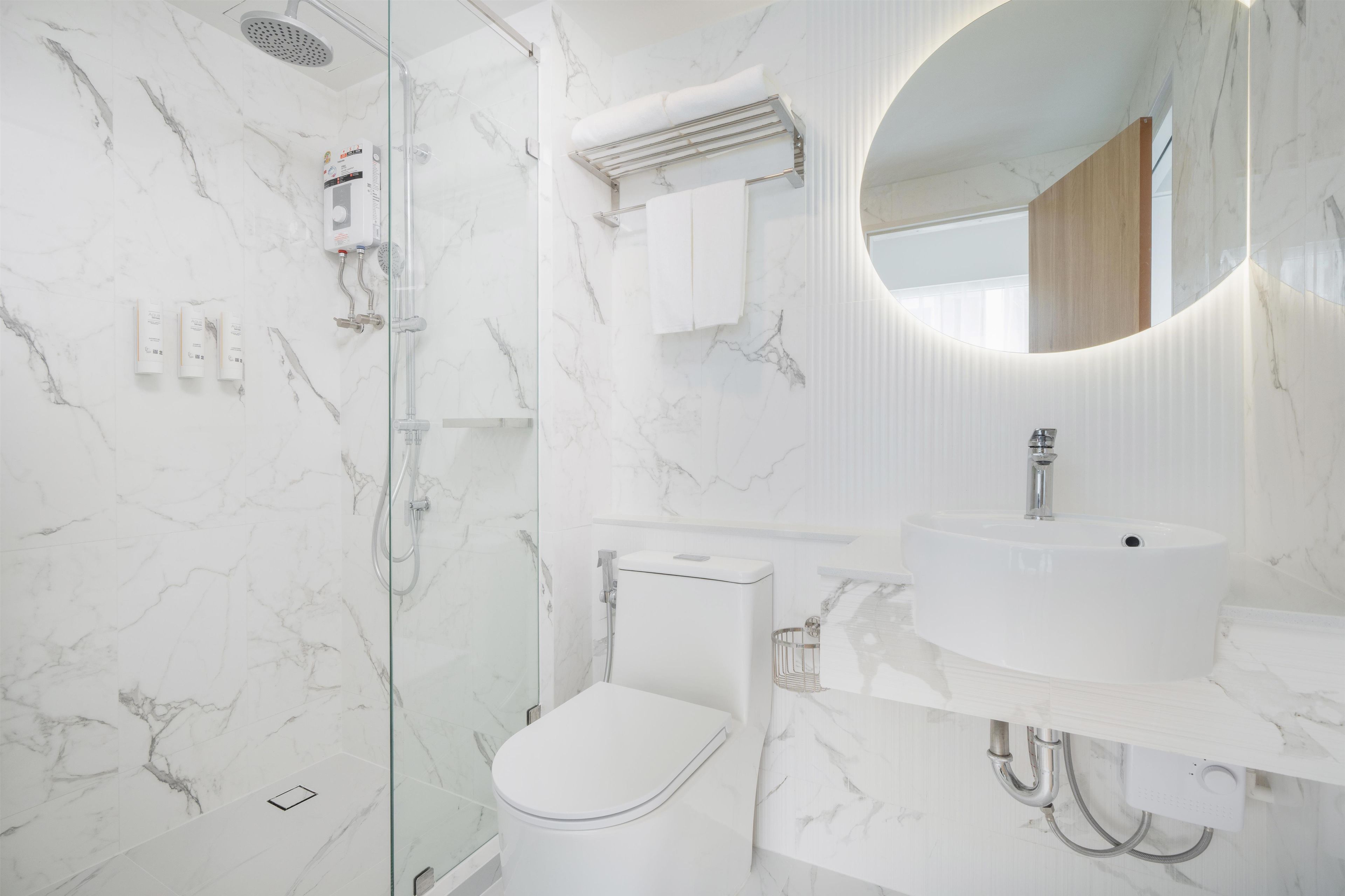 A bathroom with a glass shower enclosure, a white toilet, and a sink with a mirror above it.