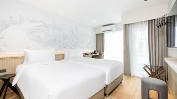 A hotel room with a large bed, a desk, a chair, and a view of a cityscape.