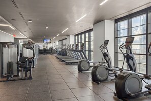 Une salle de sport équipée de tapis de course, de vélos elliptiques et d’appareils de musculation.