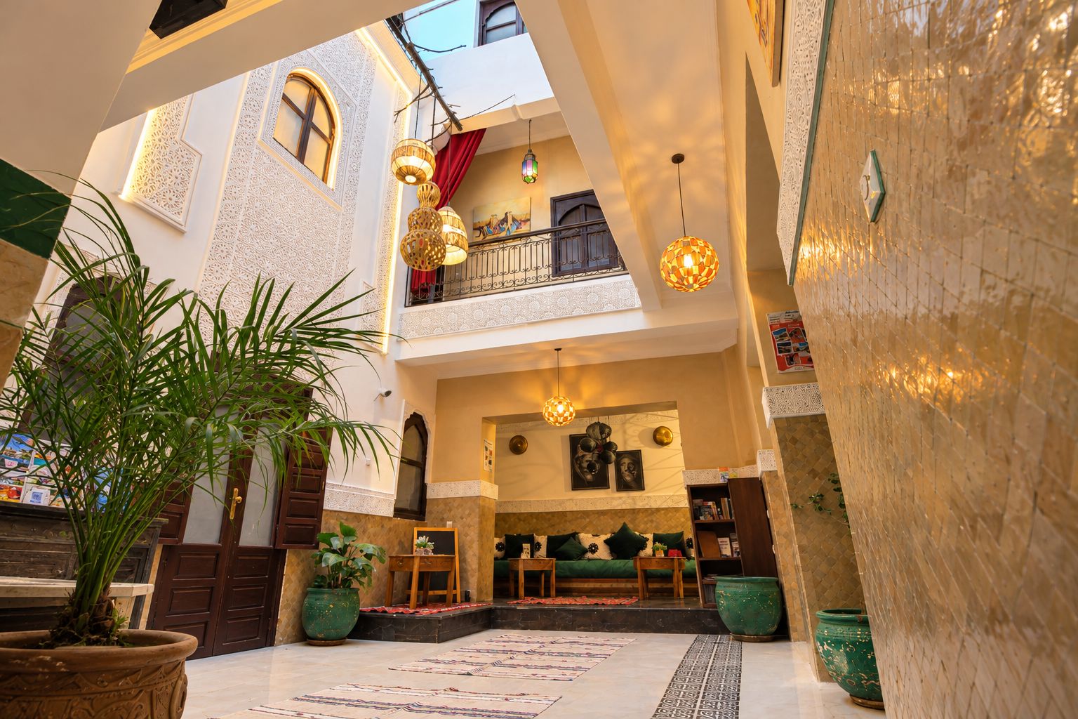 A multi-level interior with a central staircase, potted plants, and hanging lamps.