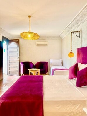 A hotel room with a bed, two armchairs, a small table, and a ceiling light fixture. - Riad Alwafaa (Marrakech)
