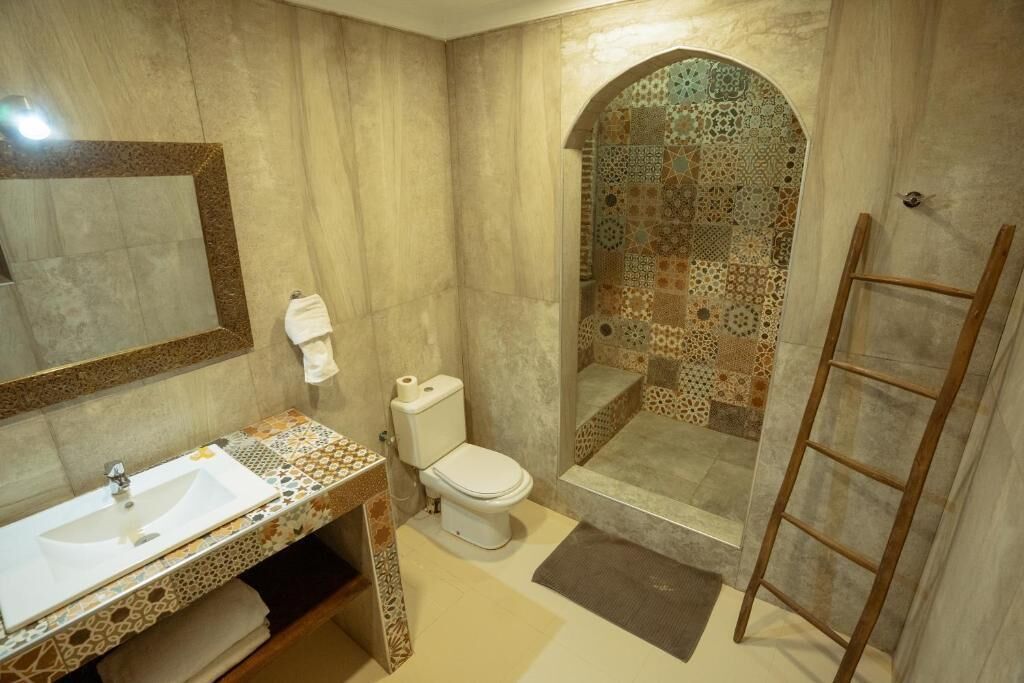 A bathroom with a sink, toilet, shower, and a mirror.