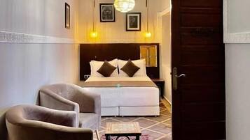 A hotel room with a bed, a chair, a small table, and a patterned rug.