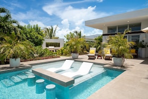 A modern pool area with lounge chairs, potted plants, and a contemporary building in the background. - Perfect for 1 Couple - Pool & Beach Access (Providenciales)