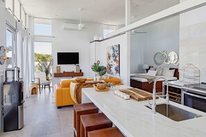 A modern kitchen with a central island, a built-in oven, and a large window. - Perfect for 1 Couple - Pool & Beach Access (Providenciales)