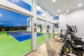 A tennis court with a net, a wall with a sign, and exercise equipment. - Perfect for 1 Couple - Pool & Beach Access (Providenciales)