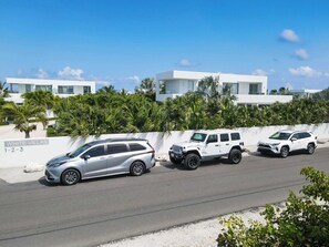 A modern white villa with a paved driveway and a white SUV parked in front. - Perfect for 1 Couple - Pool & Beach Access (Providenciales)