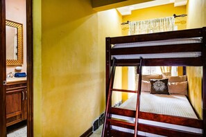 A bunk bed with a ladder, a mirror, and a window with curtains. - Beachfront 2-BR Condo with Saltwater Pool & Sunset Views (Playa Langosta)
