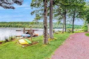 A lakeside path with kayaks, a wooden sign, and a gravel trail.