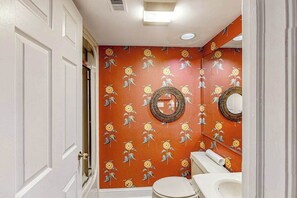Un baño con inodoro blanco, lavamanos y espejo.