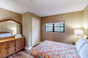 A bedroom with a bed, a dresser, a mirror, a window, and a lamp. - Serene 2BR Condo - POOL - FIREPLACE & Lake View (Lake Harmony)