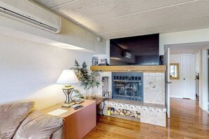 A living room with a fireplace, a sofa, a lamp, and a television mounted above the fireplace.