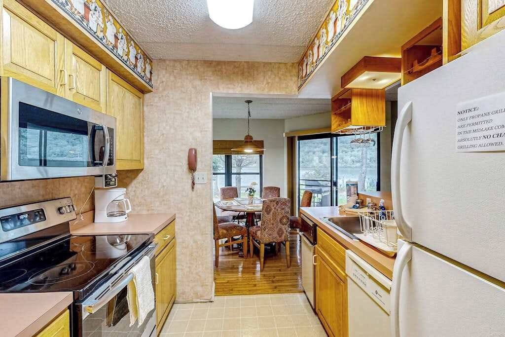 Een keuken met houten kastjes, een magnetron, een oven en een koelkast.