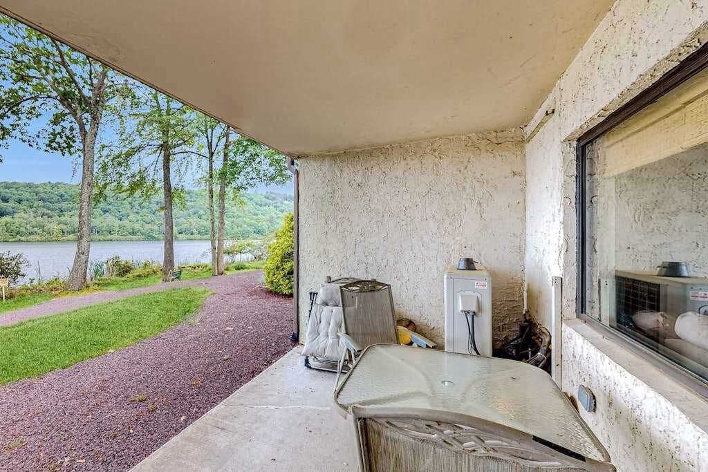 A covered outdoor area with a concrete floor, a window, and a view of a lake and trees.