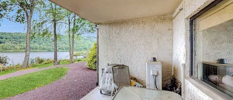 A covered outdoor area with a concrete floor, a window, and a view of a lake and trees.