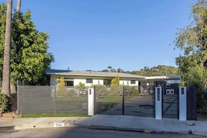 Un ingresso recintato a un edificio moderno con tetto piatto e un'apertura per garage visibile.