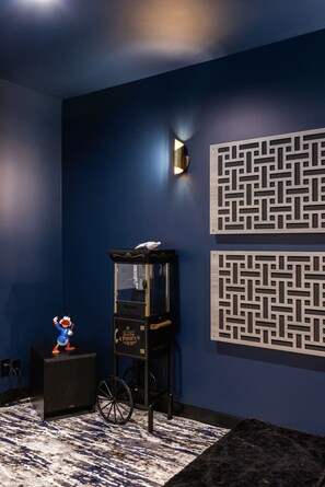 Una habitación con una pared azul oscuro, una máquina para palomitas de maíz negra y una pequeña mesa con una figurita.