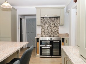 A kitchen with a double oven, a tiled backsplash, and light-colored cabinets.