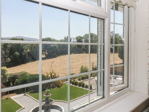 A view through a window with a clear sky, a landscaped garden, and a distant hill. - The White House (Okehampton)