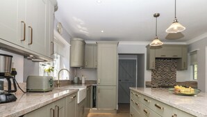 A modern kitchen with light-colored cabinets, a wooden floor, and pendant lighting. - The White House (Okehampton)