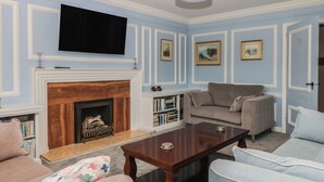 A living room with a fireplace, a television, and a sofa. - The White House (Okehampton)