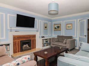 A living room with a fireplace, a television, and a sofa. - The White House (Okehampton)