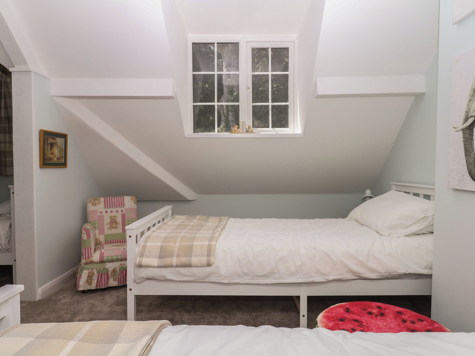 A small, single-bed room with a sloped ceiling and a window.