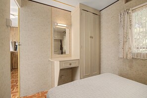 Un dormitorio con cama, cómoda, espejo y armario.