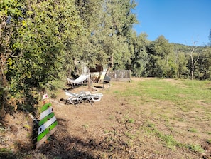 A rustic outdoor setting with a hammock, a wooden bench, and a signpost indicating directions to 'Casa' and 'Mar'.