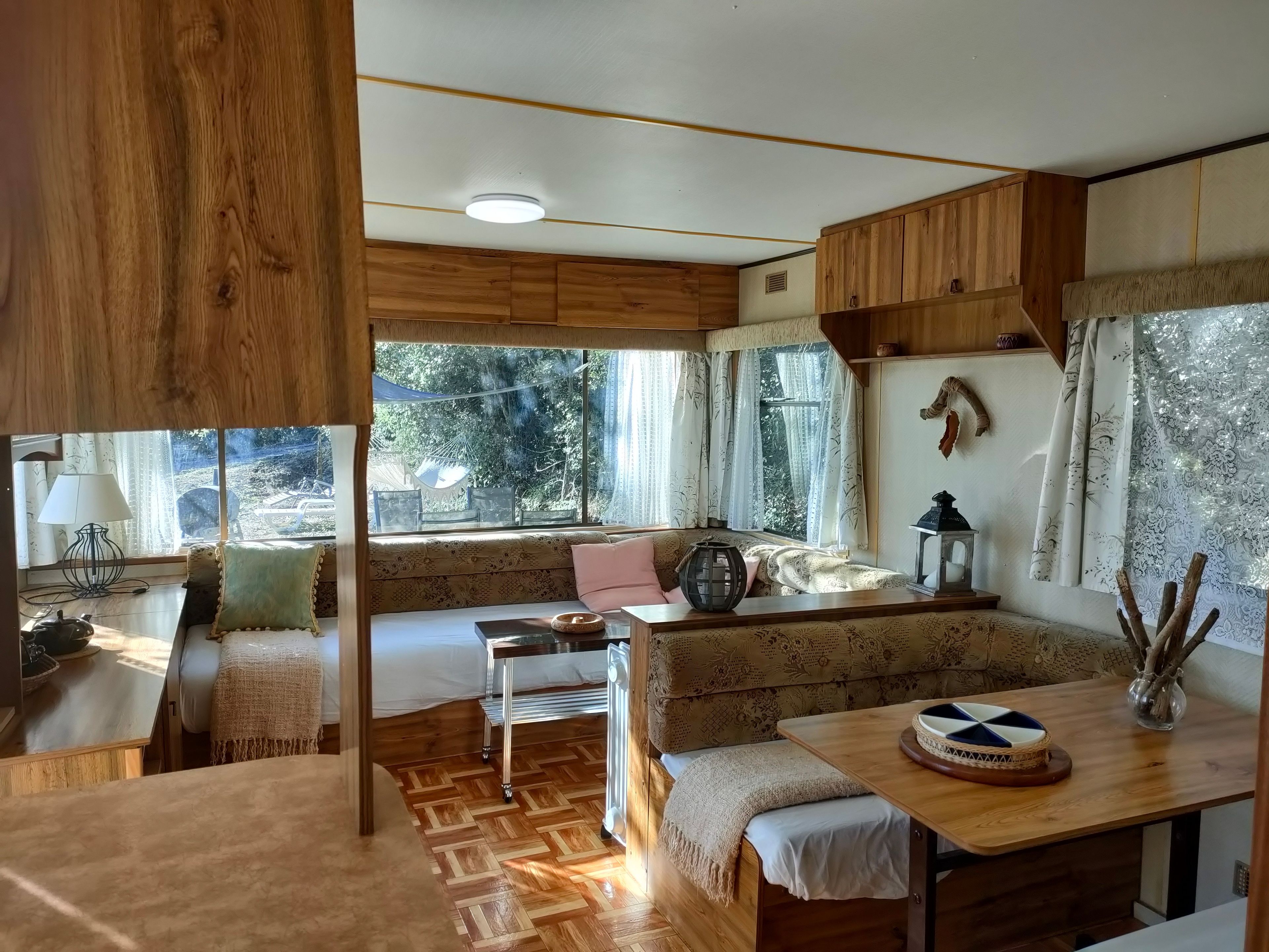 Una habitación acogedora con un banco de madera, una mesa con un cuenco decorativo y vistas al exterior.