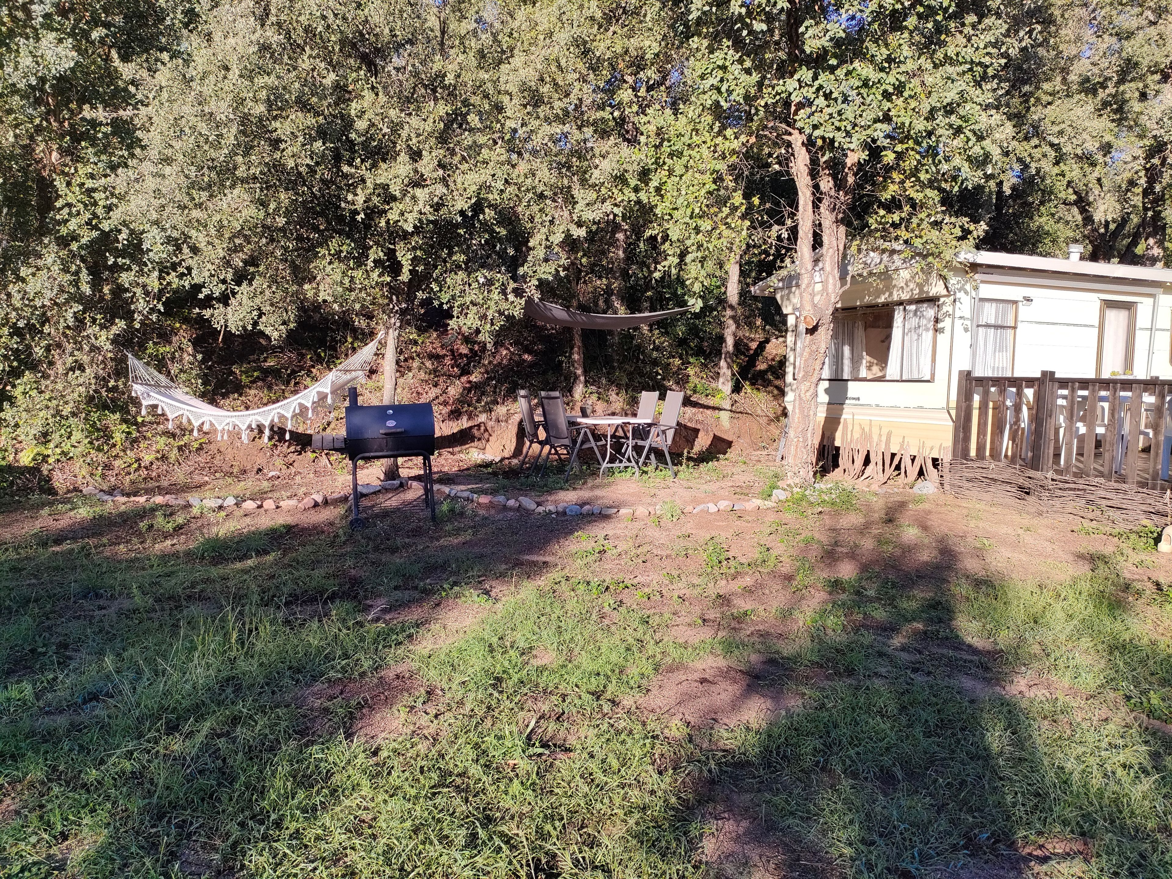 Ein Garten mit Hängematte, Grill und Sitzgelegenheit im Freien.