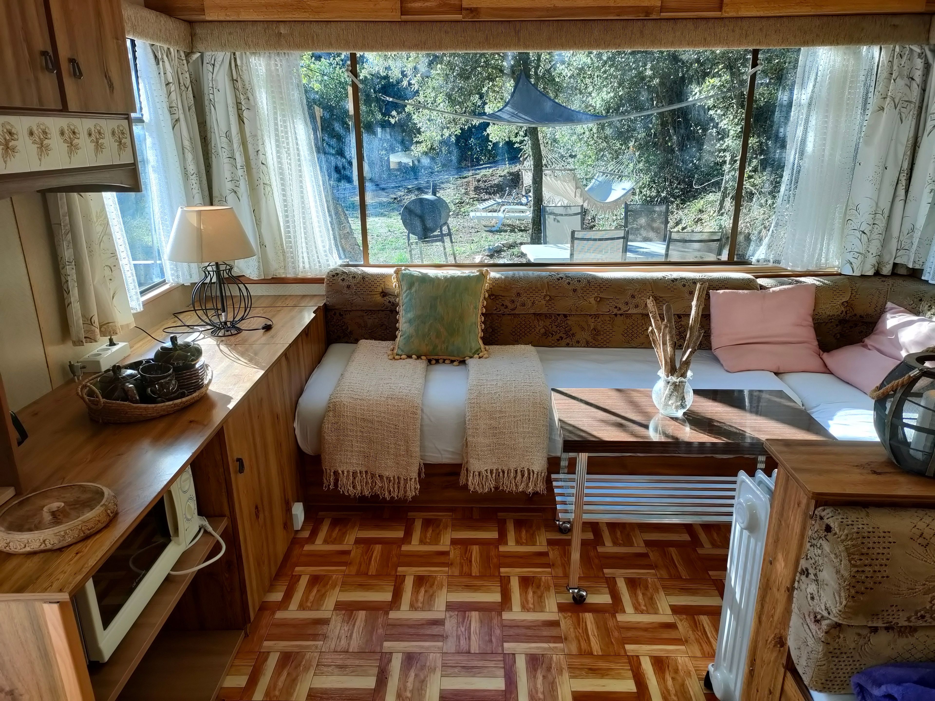 Un intérieur chaleureux avec un banc en bois, une table avec une lampe et une vue sur l’extérieur.