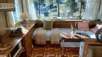 Un intérieur chaleureux avec un banc en bois, une table avec une lampe et une vue sur l’extérieur.
