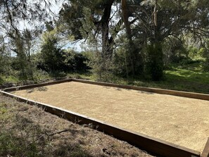 A rectangular outdoor area with a wooden border, surrounded by trees and grass. - Spacious 5-bedroom house in Florensac with AC (Florensac)