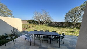 En terrasse med et bord og stole, omgivet af stenvægge og træer.
