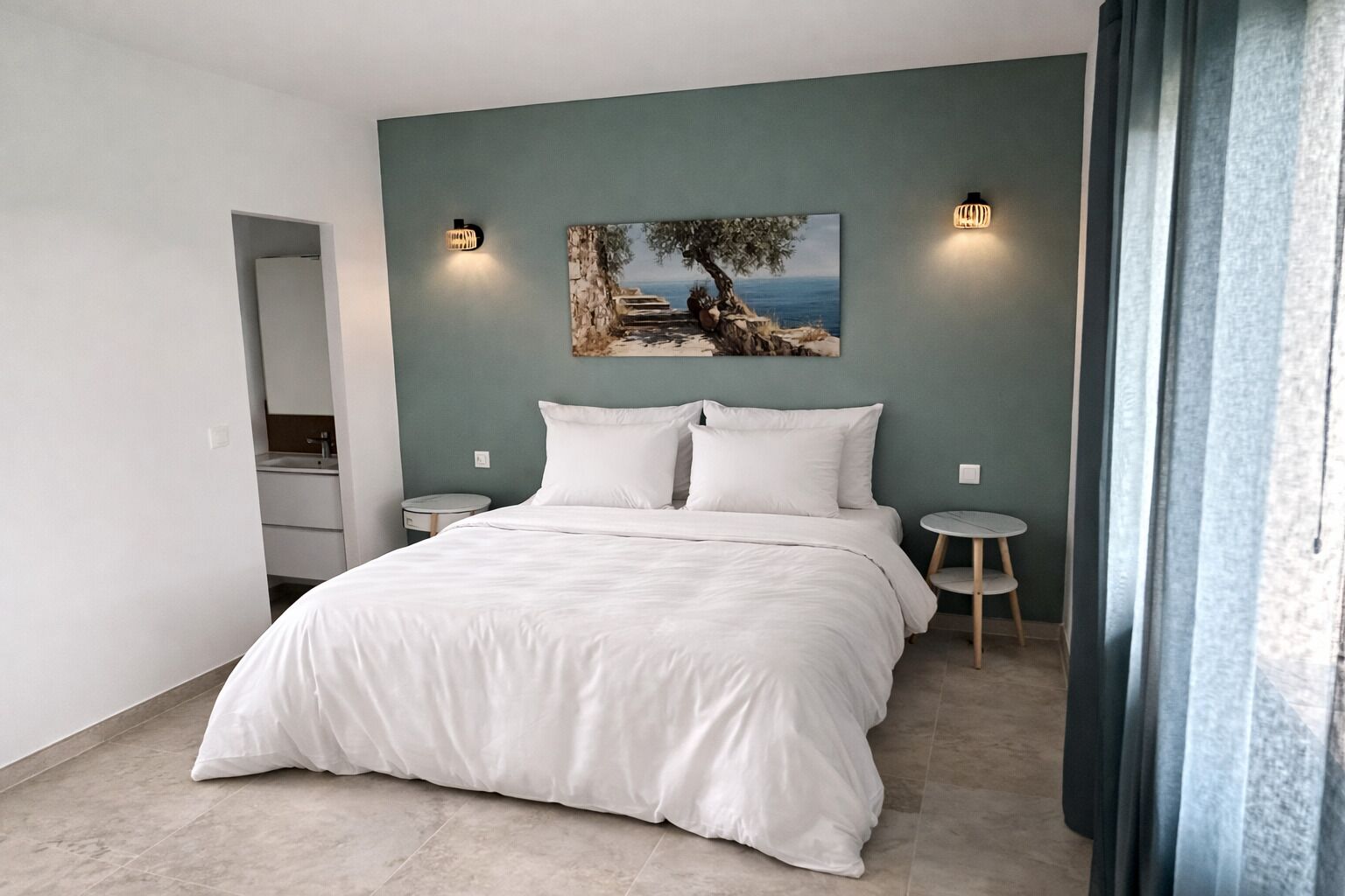 Une chambre à coucher comprenant un lit, deux tables de chevet, une œuvre d’art accrochée au mur et une porte donnant sur une autre pièce.