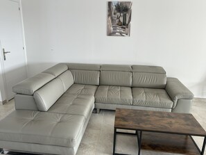Ein modulares Sofa in neutraler Farbe, ein Holztisch und ein gerahmtes Bild an der Wand.