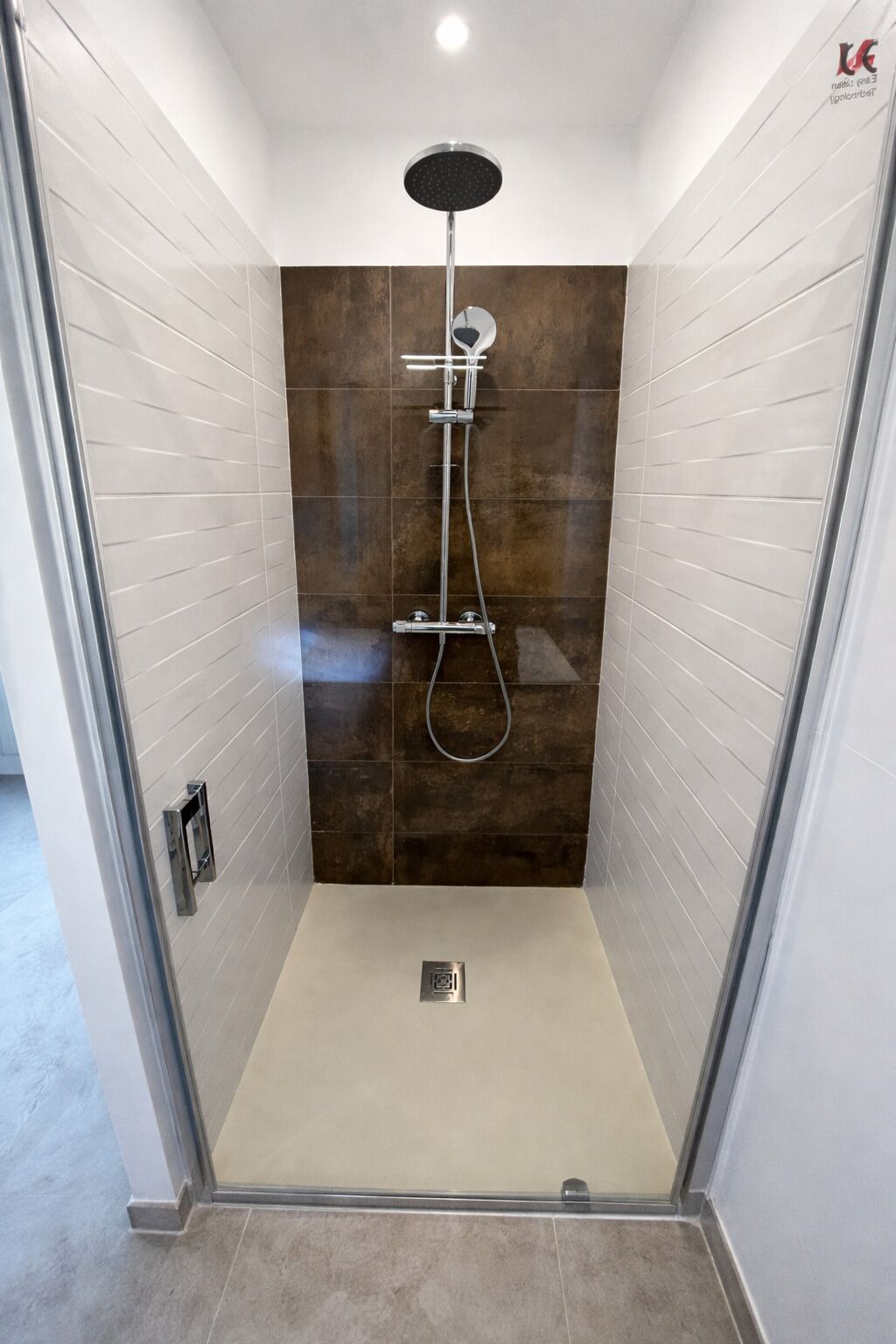 A glass-enclosed shower stall with a rain showerhead, handheld showerhead, and handheld showerhead.