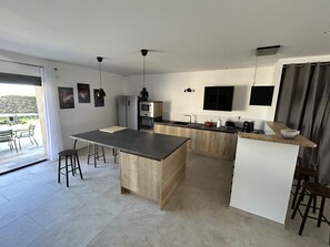 A modern kitchen with a central island, wooden cabinets, and stainless steel appliances. - Spacious 5-bedroom house in Florensac with AC (Florensac)