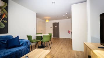 A modern living room with a sofa, a table, and a dining area with chairs.