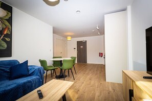 A modern living room with a sofa, a table, and a dining area with chairs. - Birmingham City Retreat No 121 (Birmingham)