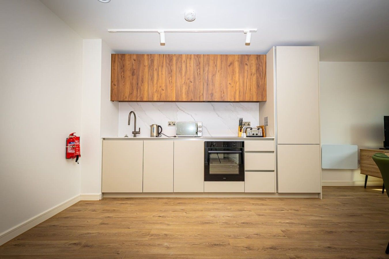 A compact kitchen with wooden cabinets, a built-in oven, and a white countertop.