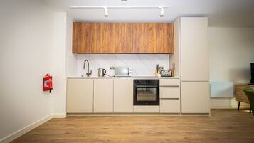 A compact kitchen with wooden cabinets, a built-in oven, and a white countertop.