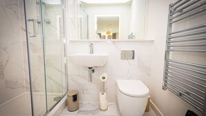 A modern bathroom with a glass shower enclosure, a sink, a toilet, and a towel rack. - Birmingham City Retreat No 121 (Birmingham)