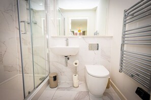 A modern bathroom with a glass shower enclosure, a sink, a toilet, and a towel rack. - Birmingham City Retreat No 121 (Birmingham)