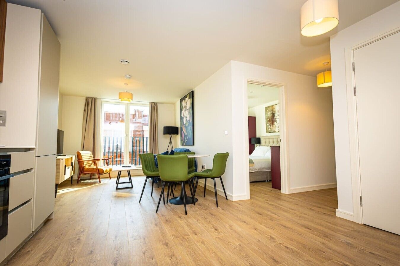 A modern apartment with a dining area, a kitchen, and a bedroom.