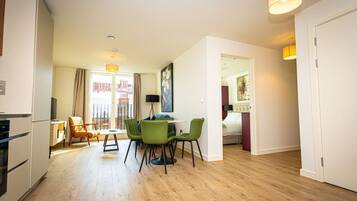 A modern apartment with a dining area, a kitchen, and a bedroom.